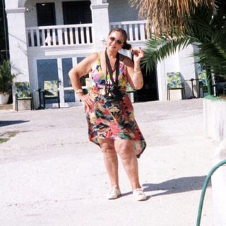 Woman using hosepipe in sunny residential area.
