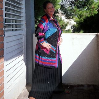 Woman wearing colorful patterned jacket and skirt outdoors.