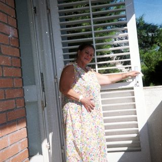 Woman standing outside near open door.