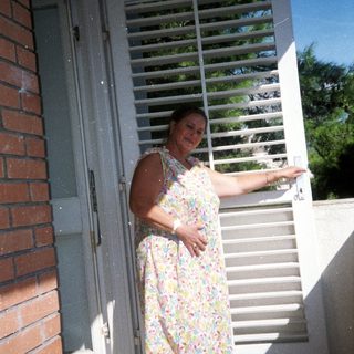 Woman standing outside near open door.