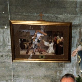 Two people posing indoors near religious statues and artwork.