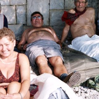 Group of five people relaxing by a rocky beach.