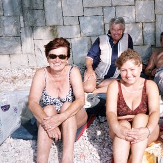 Group of five people relaxing by a rocky beach.