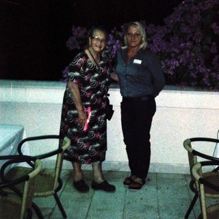 Two women posing together outdoors at night.