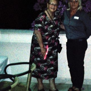 Two women posing together outdoors at night.