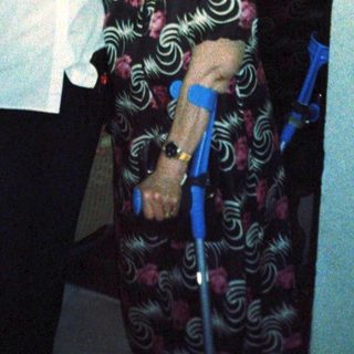 Two women posing indoors, one using walker.