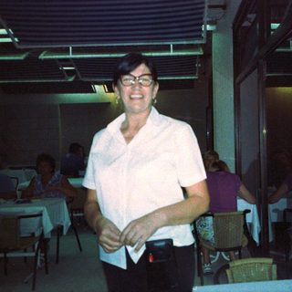 Smiling person in white shirt indoors, possibly restaurant.