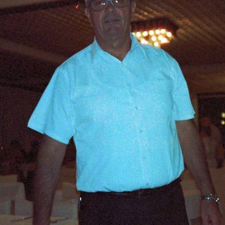 Man in light blue shirt standing indoors near boxes.