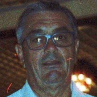 Man standing indoors at night in casual attire.