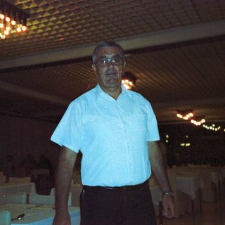 Man standing indoors at night in casual attire.