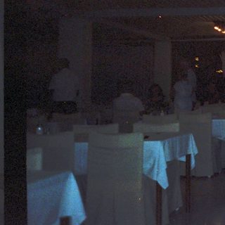 Restaurant dining area with dim lighting and tables set.
