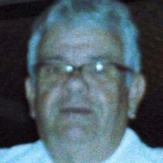 Man standing indoors near tables in dimly lit restaurant.