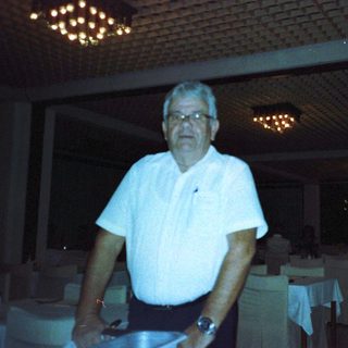 Man standing indoors near tables in dimly lit restaurant.