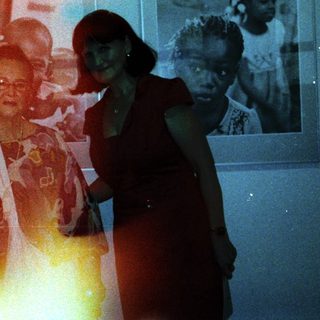 Elderly woman posing with younger woman in gallery.