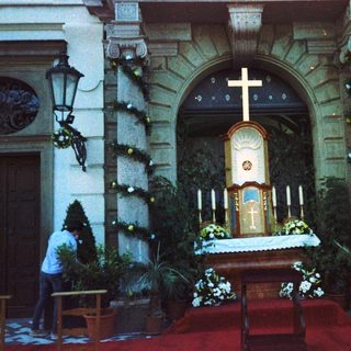 Church interior with altar, priest, and candlelit entrance.