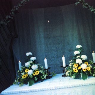 Memorial service altar with floral arrangements and candles.
