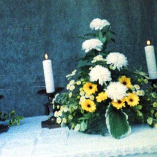 Memorial service altar with floral arrangements and candles.
