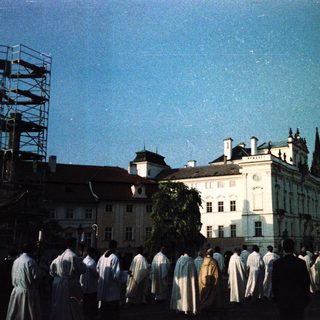 Group of people in white robes near historic buildings under scaffolding.
