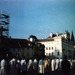 Group of people in white robes near historic buildings under scaffolding.
