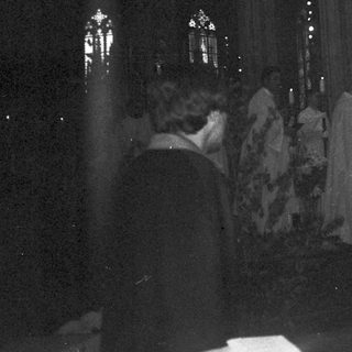 Dark church interior with lit stained-glass windows during evening service.