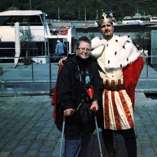 Two people posing: one in medieval costume, one using a cane.