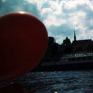 Scenic river view with boat, historic buildings, and red balloon.