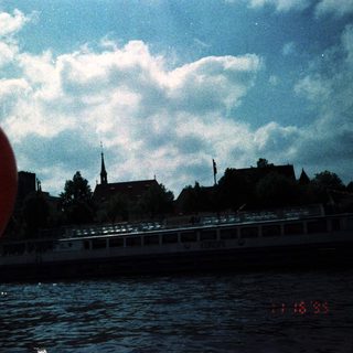 Scenic river view with boat, historic buildings, and red balloon.