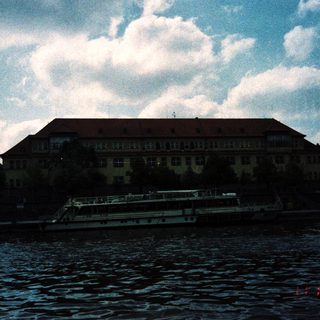 Large building by river with docked boat.