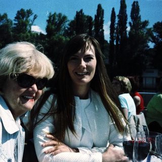 Two women smiling together at an outdoor gathering.