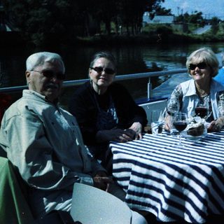 Group enjoying outdoor meal by water.