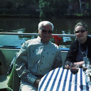 Two people enjoying drinks by a waterfront table.