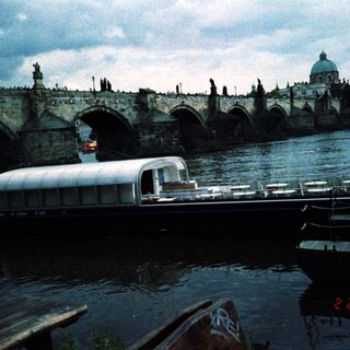Historic Prague bridge with vintage boat on river.