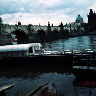Historic Prague bridge with vintage boat on river.