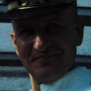 Officer in naval uniform standing on ship.