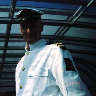 Officer in naval uniform standing on ship.