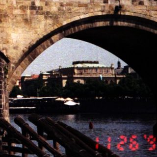 Historic stone bridge over river with pedestrians.