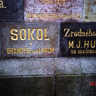 Golden plaques on stone wall: Sokol, Brandýs nad Labem, M.J. Husi.