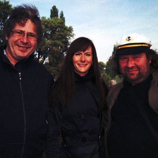 Three people posing together outdoors, smiling.