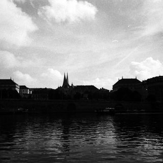 Scenic river view of historic European town with spires.