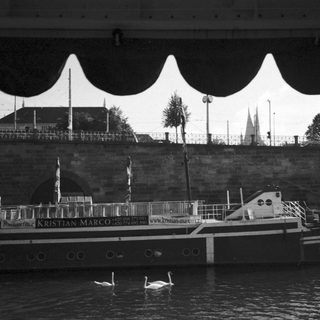 Boat named Kristian Marco on river with swans.