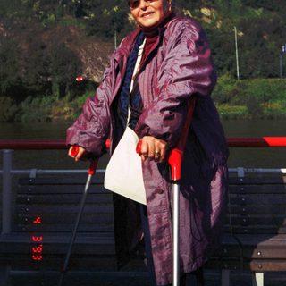 Woman in coat using walker outdoors.