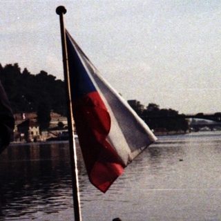 Man standing on boat near water with Czech flag.