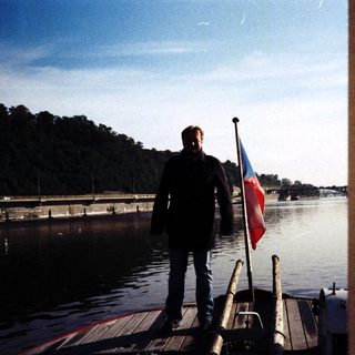 Man holding Czech flag on boat dock.