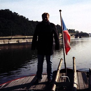 Man holding Czech flag on boat dock.