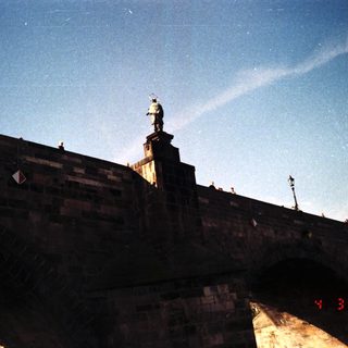 Statue atop historic stone bridge.