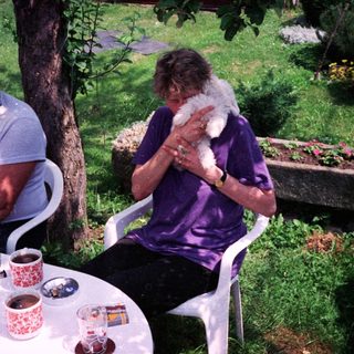 Two people outdoors enjoying drinks and conversation with a dog.