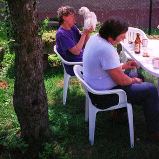 Two women outdoors with a small white dog.
