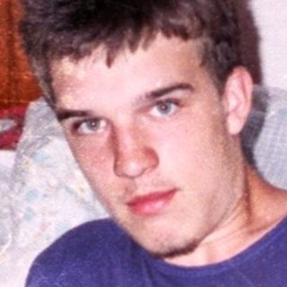 Young man holding game card on bed.