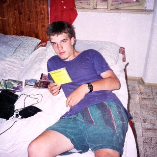 Young man holding game card on bed.