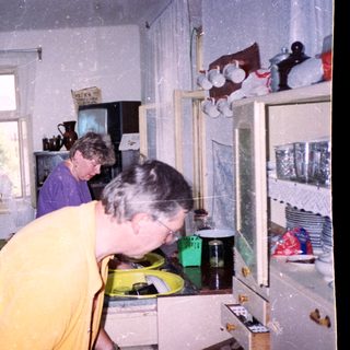 Two women in a kitchen during snowfall.